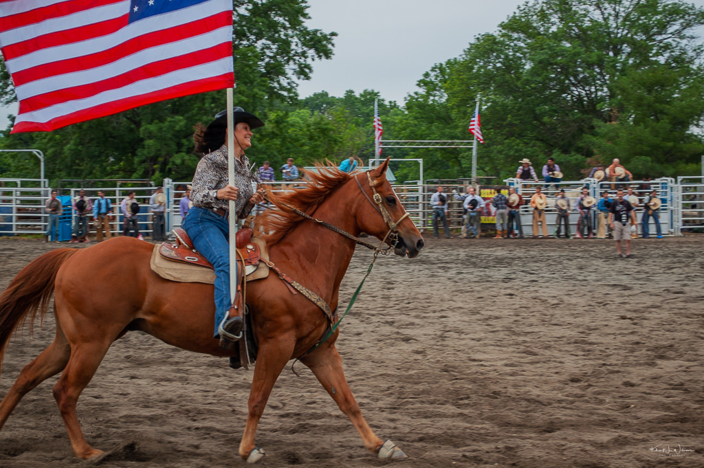 cowgirl riding horse with american flag