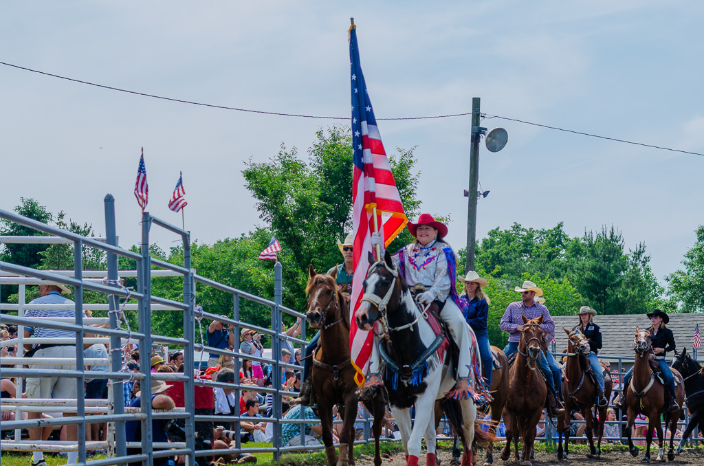 cowboys and cowgirls on horse back flag procession