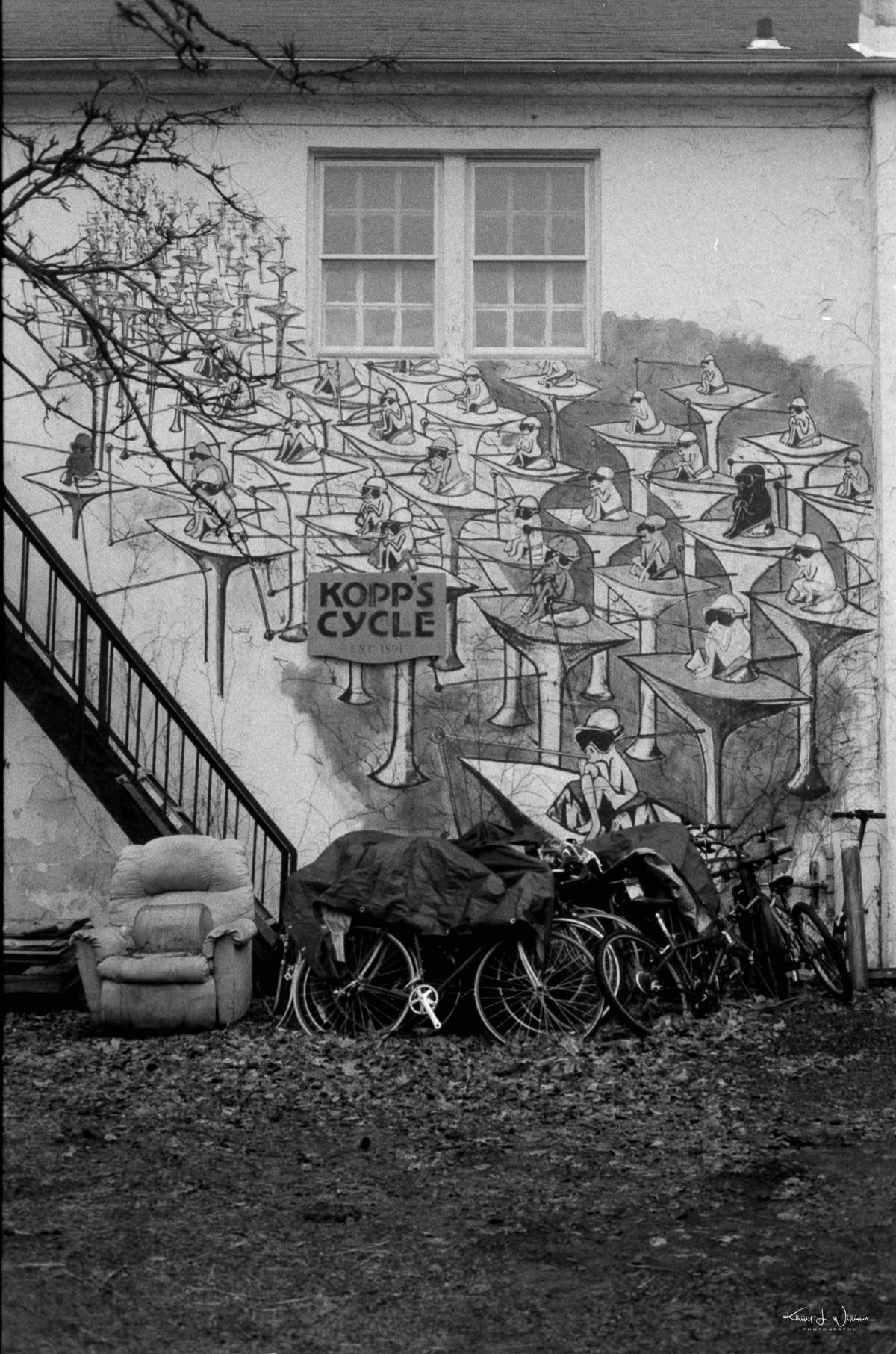 bicycles and abandoned chair on the side of the mural outside kopp's cycle.